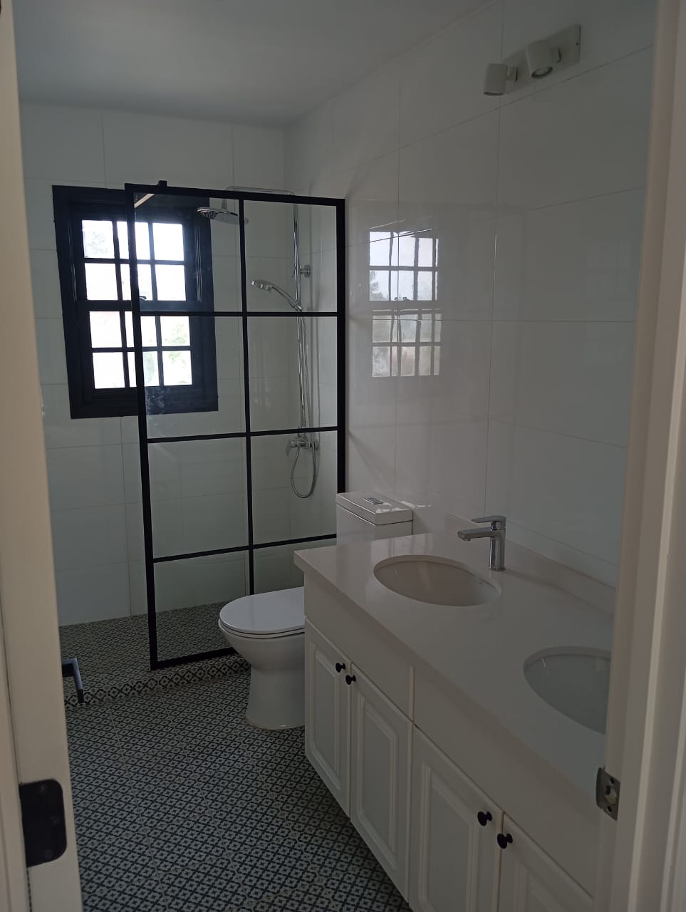 Baño remodelado con ducha de vidrio y piso de mosaico