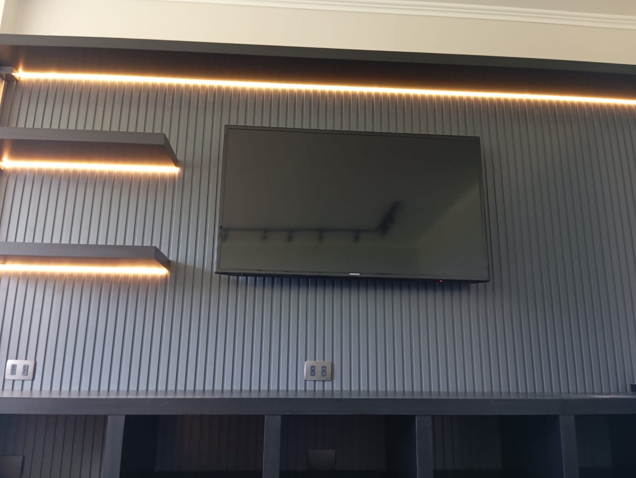 Living con revestimiento de madera y terminaciones con iluminación LED