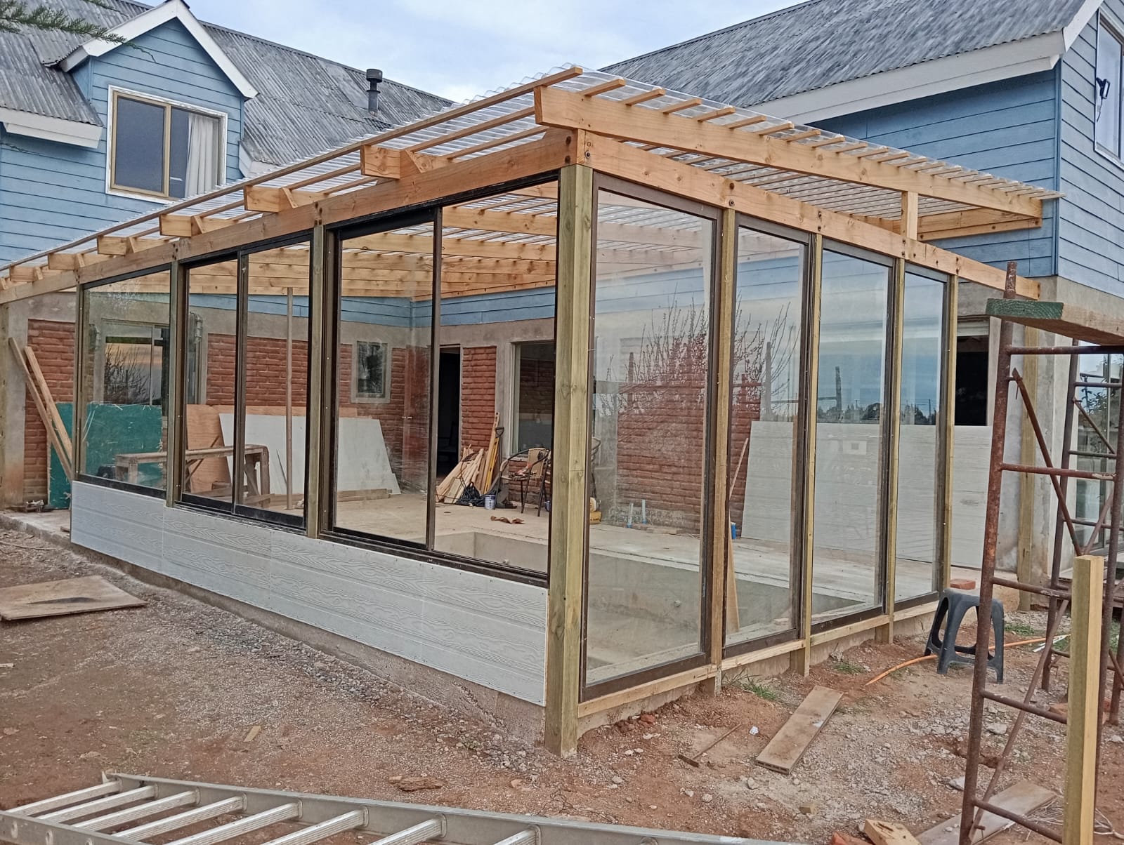 Terraza vidriada con estructura de madera y ventanales termopanel construida por Constructora Pilpilén